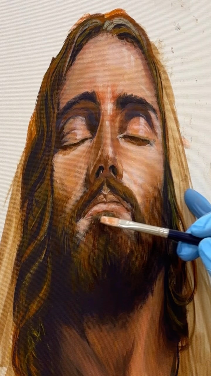 Fran trabajando con pincel en un retrato al óleo de Cristo
